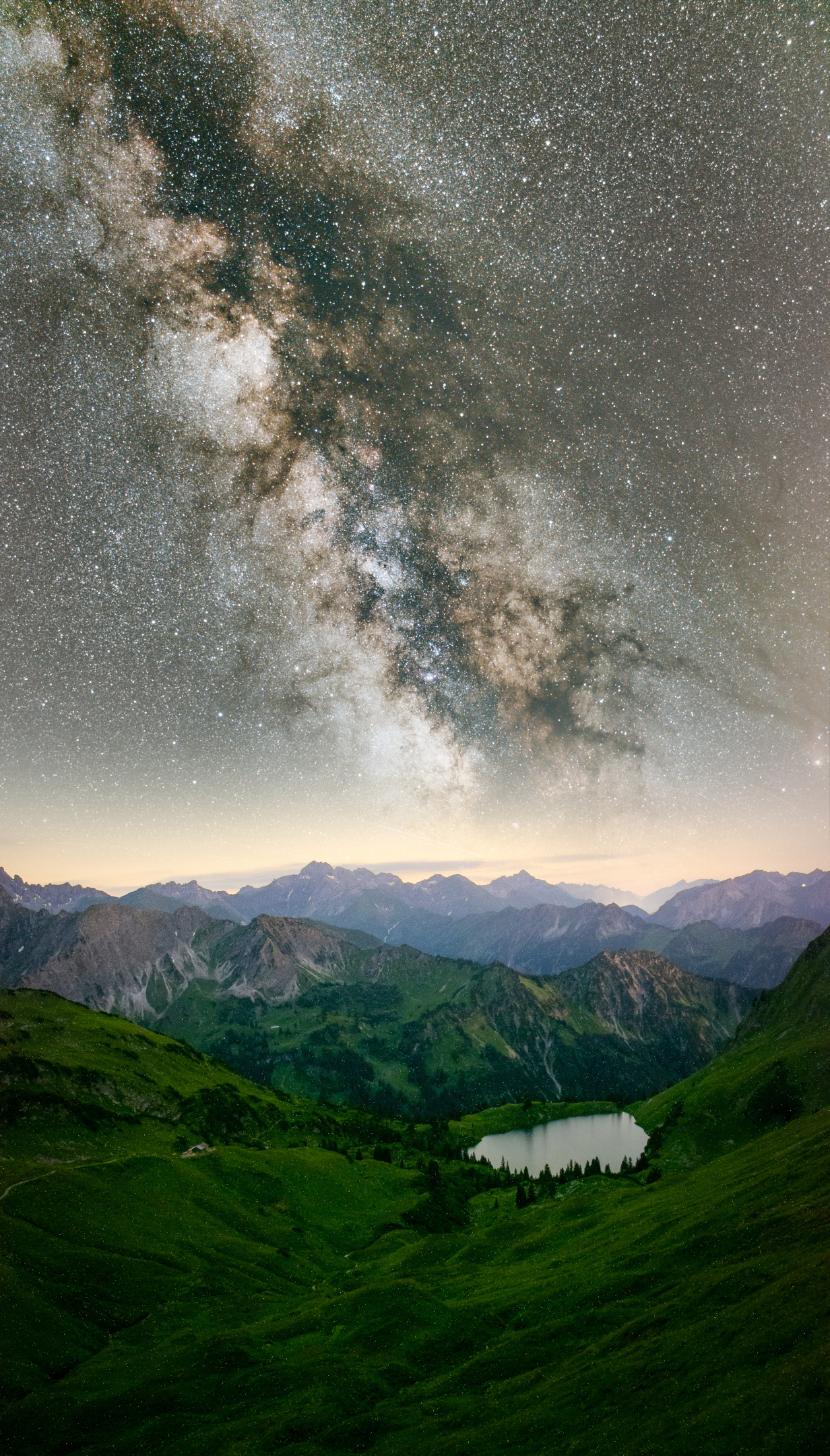 Image of the Milky way galaxy visible above some mountains and a lake